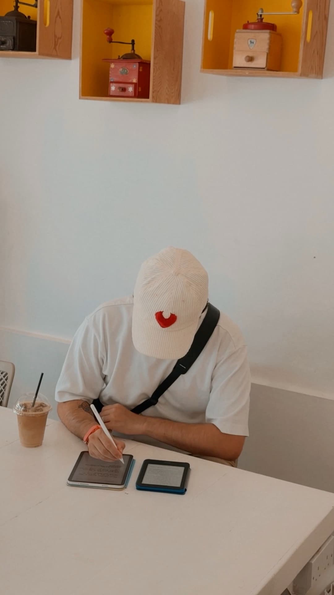 Writing with an Apple Pencil at a café table, an iced coffee close by